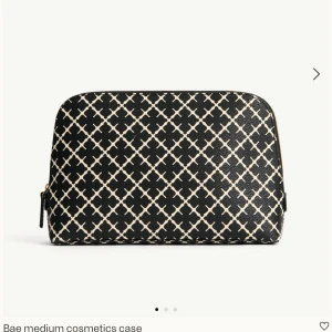 Svartvit necessär från By Malene Birger - Snygg necessär från By Malene Birger i svart och vitt med rutigt mönster. Tillverkad i syntetmaterial med dragkedja upptill och praktiskt innerfack med resår. Perfekt för smink eller småprylar i väskan.