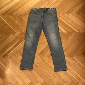 Slim fit jeans från Jack & Jones - Snygga ljusblå slim fit jeans från Jack & Jones, modell Glenn. Klassisk femficksdesign, normalhög midja och raka ben. Tillverkade i mjukt bomullsjeans med lätt tvättad look och diskreta slitningar. Perfekta för en avslappnad stil.