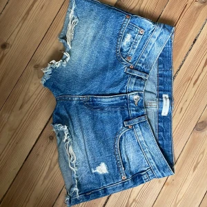 Lågmidjade jeansshorts  - Säljer igen då dom var för stora för mig.Snygga lågmidjade korta jeansshorts med slitningar i storlek 32 från Gina Tricot. Använda fåtal gånger. Säljes i befintlig skick se bilderna☀️midjemått rakt över: 38cm original pris 400.