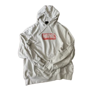 Vit Marvel hoodie från H&M XL - Säljer en vit hoodie från H&M i samarbete med Marvel. Tröjan har en stor röd Marvel-logga på bröstet, huva med snörning och känguruficka framtill. 