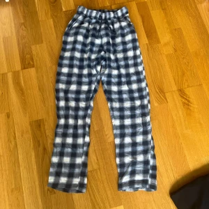 Rutiga pyjamasbyxor - Snygga rutiga byxor i blått och vitt, tillverkade i 100% bomull. De har resår i midjan för extra komfort och en avslappnad passform. Perfekta för chill dagar hemma eller när du vill ha en soft stil.