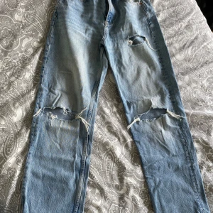 Ljusblå slitna jeans från Gina Tricot - Petite - Ljusblå jeans med flera slitningar och hål på benen från g perfect jeans. Klassisk femficksmodell med raka ben och normal passform. Perfekta för en avslappnad och trendig look. Passar dig som är ca 160cm lång.