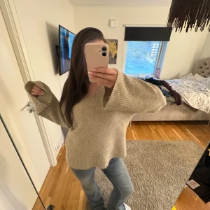 Gina Tricot stickad tröja  - Mysig beige stickad tröja från Gina Tricot i storlek S. Tröjan har lång ärm, bred ribbad mudd vid ärmslut och en avslappnad passform. Perfekt för lager-på-lager och enkel att matcha med jeans eller kjol.