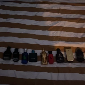 Mix av herrparfymer från olika märken - Säljer ett gäng herrparfymer i olika flaskor och färger, bland annat blå, svart, guld och röd. Flera kända märken syns, bland annat flaskor med unika former som en guldig och en röd med kroppssiluett. Perfekt för dig som vill testa olika dofter.