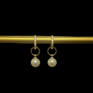Guldörhängen med pärlor - Eleganta örhängen i guld med rund ring och hängande vita pärlor. Perfekta för att ge en lyxig touch till din stil. Klassisk design med gnistrande detaljer på ringen och tidlös pärla som hänge.