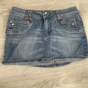 Jeanskjol med fickor och broderad detalj - Säljer en klassisk blå jeanskjol med fram- och bakfickor samt en snygg broderad detalj på baksidan. Knappt använd och säljer för att den är för liten för mig! Mått 37 cm tvärs över💗
