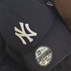 New Era NY keps i mörkblå - 1 klassisk New Era 9FORTY keps med NY-logga. Justerbar passform och böjd skärm. 