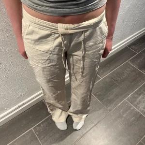 Beige linnebyxor från bpc bonprix collection - Säljer ett par beige linnebyxor från bpc bonprix collection i storlek 34. Byxorna har dragsko i midjan, raka ben och stora fickor framtill. Perfekta för en avslappnad och stilren look. De är lite slitna vid benen. Hör av er vid kommande frågor eller om fler bilder.💛