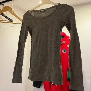 Mörkgrå långärmad tröja från H&M - Säljer en enkel och stilren mörkgrå långärmad tröja från H&M. Tröjan har rund halsringning och är tillverkad i mjuk bomull, perfekt för lager-på-lager eller som basplagg.