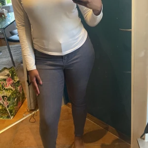 Grå skinny jeans - Säljer ett par grå skinny jeans med hög midja. Jeansen har klassisk femficksdesign och stängs med knapp och dragkedja. Snygg passform som sitter tight hela vägen ner.