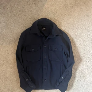 Navy overshirt - Säljer denna feta och trendiga overshirten. Passar till allt och är väldigt stilren. Endast använd ett fåtal gångar och har inga defekter. Den är i storlek S men passar XS. Den är inte lång eller bred, vilket gör att den sitter väldigt bra.