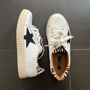 Vita trendiga sneakers  - Så sjukt snygga skor med en svart läderstjärna på sidan och zebramönstrad detalj vid hälen!🙌🏼Unika och perfekta för att lyfta en outfit