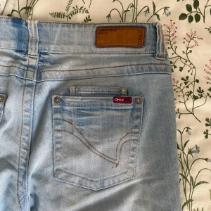 Ljusblå jeans från Only - Snygga ljusblå jeans från Only med klassisk femficksdesign och knappgylf. Perfekta nu för sommaren! De är lowwaist och flared. Två hål vid skrevet men går att sy ihop.
