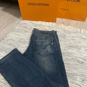 Dondup jeans  - Säljer ett par klassiska blå Dondup jeans med snygg tvätt och diskreta slitningar. Modellen har raka ben och normal passform, med fem fickor och dragkedja. Perfekta för dig som gillar stilrena jeans med en modern touch.