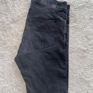 Mörkgrå jeansbyxor från Tiger of Sweden - Säljer ett par svarta  jeansbyxor från Tiger of Sweden, modell Pistolero. Klassisk femficksdesign med snygga detaljer och diskret logga vid fickan. Nypris ligger på 1799kr‼️bilden med människan visar endast passformen men färgen är mörkare! Kan gå ner i pris vid snabb affär 🤝