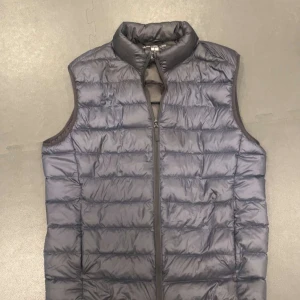 Mörkblå dunväst med dragkedja - Säljer en stilren mörkblå dunväst med riktigt skön passform  i mörkblå, väldigt praktiskt då den går att vika ihop med i en påse som medföljer. Tunn och lätt väldigt skönt nu i vår/sommar. Storlek XS! Fler bilder finns att be om!