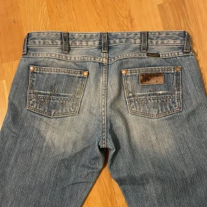 💓Lågmidjade Wrangler jeans💓 - Säljer ett par klassiska blå jeans från Wrangler med bootcut passform. Säljer då de aldrig kommer till användning! Köpta på en secondhand för 600kr som in princip nyskick!❤️midjemått rakt över: 38cm innerbenslängd: 73cm! Pris kan diskuteras