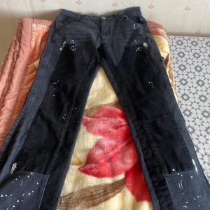 Svarta cargopants med vita färgstänk - Säljer ett par svarta cargopants med flera fickor på sidorna och coola vita färgstänk över hela byxorna. Byxorna har rak passform och klassisk cargostil, perfekta för en avslappnad streetlook.