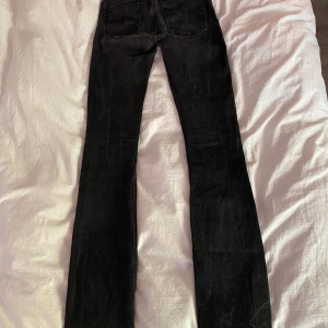 Nudie Jeans - Säljer ett par svarta jeans från Nudie Jeans med klassisk femficksdesign. Byxorna har en rak passform och normal midja. Storlek W27 L34