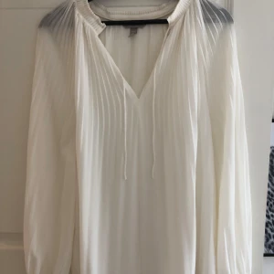 Vit elegant blus - Elegant fin blus med fina detaljer,tunt tyg som faller fint. Endast använd vid ett tillfälle,så väldigt fint skick. 