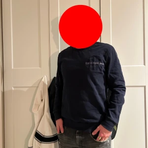 Mörkblå sweatshirt från Calvin Klein Jeans - Säljer en stilren mörkblå sweatshirt från Calvin Klein Jeans med diskret logga på bröstet. Tröjan har rund halsringning och långa ärmar, perfekt för en avslappnad och snygg look.