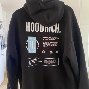 Svart hoodie från Hoodrich - Säljer en svart hoodie från Hoodrich med tryck både fram och bak samt på ärmen. Hoodien har huva med dragsko och en stor magficka. Perfekt för dig som gillar streetwear och vill ha en snygg och bekväm tröja.