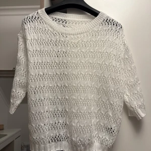 Vit stickad tröja från SHEIN - Säljer en vit stickad tröja från SHEIN med ett luftigt, hålmönstrat stickat material. Tröjan har rund halsringning och trekvartsärm. Perfekt för lager-på-lager och ger en fräsch look till din outfit.