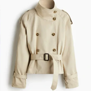 Beige trenchcoat med bälte och hög krage -  Beige trenchcoat slutsåld på hemsidan. Jackan är i storlek L men jag är vanligtvis S och den sitter jättebra på mig! 450 kr.