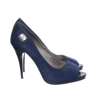 Vintage Blå pumps med öppen tå från Replay - Snygga blå pumps från Replay med öppen tå och hög klack. Skorna har en elegant siluett och är tillverkade i ett tygmaterial med en liten metallbricka vid hälen. Perfekta för dig som vill sticka ut.🥰