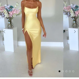 Ljusgul långklänning i satin med slits - Supersnygg ljusgul långklänning i satin med smala axelband och öppen rygg med snörning. Klänningen har en hög slits framtill och figurnära passform. Perfekt för bal! Säljer då jag köpt en annan klänning! Helt ny med lappar och allt. Pris kan diskuteras 