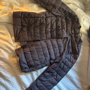 Mörkgrå dunjacka från Uniqlo - Säljer en mörkgrå dunjacka från Uniqlo i storlek S. Jackan har lång ärm, dragkedja framtill och är quiltad med en smidig, minimalistisk design. Perfekt för lager-på-lager och enkel att packa med sig. Använd men ser ut som ny!
