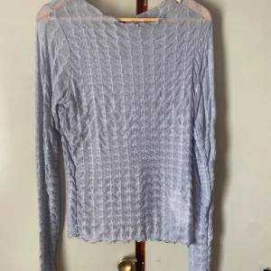 Ljusblå långärmad topp från Gina Tricot - Säljer en ljusblå långärmad topp från Gina Tricot. Toppen är tunn och har ett vågigt, transparent mönster i tyget som ger en snygg struktur. Perfekt att styla lager på lager eller som den är. Helt oanvänd