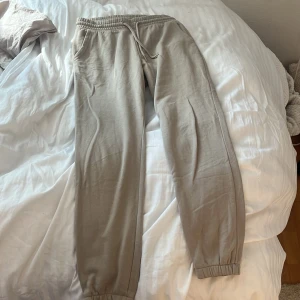 Beige mjukisbyxor från Divided - Säljer ett par beige mjukisbyxor från Divided med resår i midjan och benslut samt dragsko. Byxorna har sidofickor och är tillverkade i en mjuk bomullsblandning. Perfekta för en avslappnad stil.