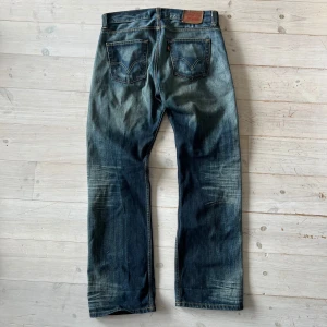 Levi's 506 Standard jeans - Klassiska blå Levi's 506 Standard jeans med raka ben och femficksmodell. Jeansen har tydliga slitningar och kontrastsömmar samt läderpatch bak i midjan. Perfekta för en avslappnad stil. Kom med bud!