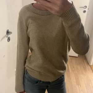 Beige stickad tröja från Vila - Mysig beige stickad tröja från Vila med rund halsringning och ribbade muddar vid ärmslut och nederkant. Skönt och stabilt material. Använt en del men är i bra skick och inga tecken på några skador. 