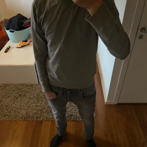 Grå slim fit tröja från H&M - Snygg grå tröja från H&M i slim fit-modell. Tröjan har rund halsringning, långa ärmar och är tillverkad i mjuk bomullsmix. Perfekt för dig som gillar en enkel och stilren look. Passar till jeans eller chinos för en clean vibe.
