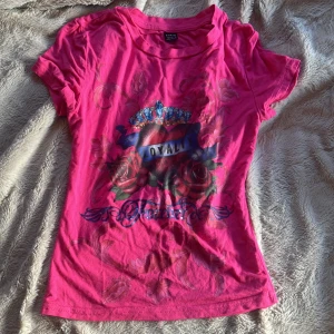 Rosa t-shirt med tryck   - Cool rosa t-shirt från SHEIN med stort tryck på framsidan som visar ett hjärta, rosor och en krona med texten 'LOYALTY'. T-shirten har rund hals och korta ärmar, och är gjord i mjuk bomull. Perfekt för dig som gillar statement-plagg och färg!