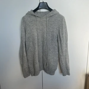 Kasmir hoodie - Grå kasmir hoodie med huva och snörning framtill. Tröjan är i bra skick ungefär 8/10. Perfekt för chill dagar och när du vill ha det extra bekvämt.