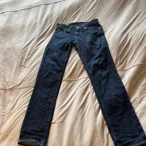 Levi's 511 mörkblå jeans W29 L32 - Snygga Levi's 511 jeans i mörkblå tvätt med klassisk femficksdesign och raka ben. Jeansen har låg midja och är tillverkade i slitstarkt bomullsmaterial med jeanskänsla. Passformen är slim och de har detaljer som nitar och läderpatch bak.