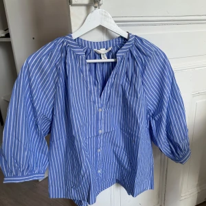 Blåvit randig skjorta från H&M XS - Snygg blå skjorta med vita ränder från H&M i storlek XS. Skjortan har trekvartsärmar, knappar framtill och en avslappnad passform. Perfekt för dig som gillar en fräsch och stilren look.