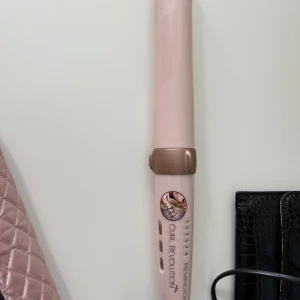 Remington Curl Revolution locktång - Säljer en Remington Curl Revolution locktång i ljusrosa med roséguldsdetaljer. Kommer med en quiltad, rosa värmetålig förvaringsväska med dragkedja. Perfekt för att skapa snygga lockar snabbt och enkelt.