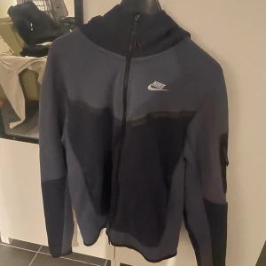 Nike marinblå hoodie med dragkedja - Nike tech hoodie i marinblått, den är i storlek S och knappt använd, fortfarande i nyskick, priset kan gå ner med snabb affär.