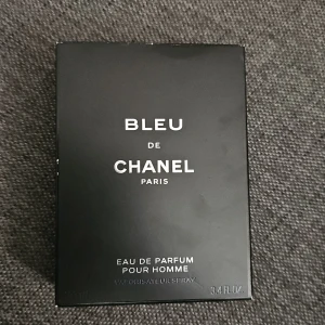 Bleu de Chanel Eau de Parfum 100ml - Bleu de Chanel Eau de Parfum för herrar, 100 ml. Flaskan är stilren och fyrkantig i mörkblått glas med silverdetaljer och svart lock. En ikonisk doft från Chanel som utstrålar elegans och modern maskulinitet.