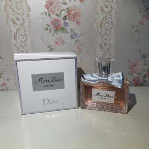 Miss Dior Parfum 80ml från Dior - Miss Dior Parfum från Dior i en lyxig, rektangulär glasflaska med ljusrosa doft och en söt silverfärgad rosett vid halsen. Kommer med original vit kartong med silverdetaljer. Flaskan rymmer 80 ml och har en elegant och feminin design.