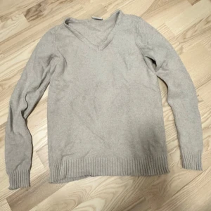 Beige v-ringad stickad tröja Vila XS - Mysig beige stickad tröja från Vila i storlek XS. Tröjan har v-ringning, långa ärmar och bred ribbad kant vid ärmslut och nederkant. Perfekt för lager-på-lager och chill dagar.