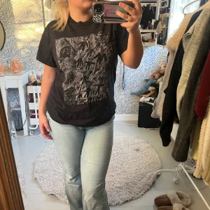 Svart t-shirt med radiohead tryck - Svart t-shirt med coolt grafiskt tryck i vitt på framsidan. Trycket har en handritad känsla med figurer och mönster. T-shirten har rund hals och korta ärmar, och är i klassisk normal passform. Perfekt för dig som gillar streetstyle och unika prints. 100% bomull