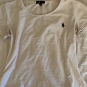 Vit Ralph lauren tshirt 💝💝 - Fin vit t-shirt från Polo Ralph Lauren med klassisk rund hals och korta ärmar. Diskret broderad logga i svart på bröstet. Mjuk och skön bomull som passar perfekt till jeans eller shorts. Enkel och stilren design. I storlek L men är XS