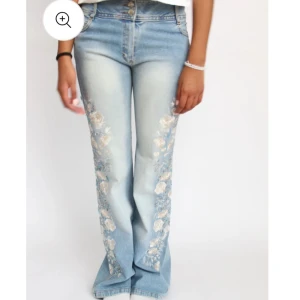 Ljusblå bootcut jeans med blommigt mönster - Säljer ett par ljusblå bootcut jeans med blommigt mönster längs benen. Dom är slitna längst ner så skickar bild på det privat. Jag är 167 och dom sitter bra men lite långt på mig men dom går att klippa eller vicka upp eftersom blommönstret inte går hela vägen ner! Säljer bara vid bra pris eftersom det är så unika!🩵
