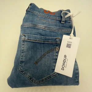 Ljusblå jeans från Dondup, stl 30 - Snygga ljusblå jeans från Dondup i klassisk femficksmodell. Jeansen har en rak passform och är tillverkade i mjukt bomullsjeansmaterial. Perfekta för dig som gillar en stilren och avslappnad look. Märkeslapp bak och snygga detaljer vid fickorna. Nypris 3 000kr 