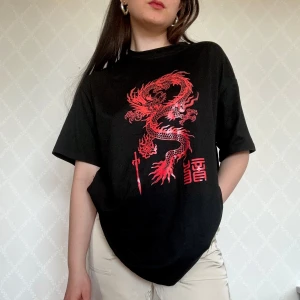 Svart t-shirt med röd drake - Svart t-shirt med en stor röd drake tryckt på framsidan, samt asiatiska tecken och ett svärd!🤗Supercool att till exempel dansa i :)